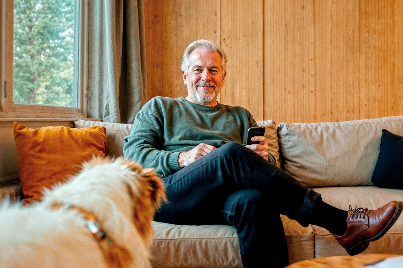 Man op de bank met smartphone in hand