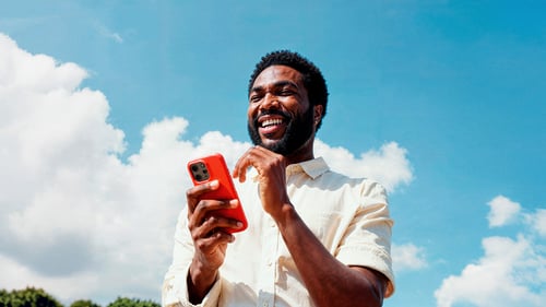Blij kijkende man met smartphone in zijn hand