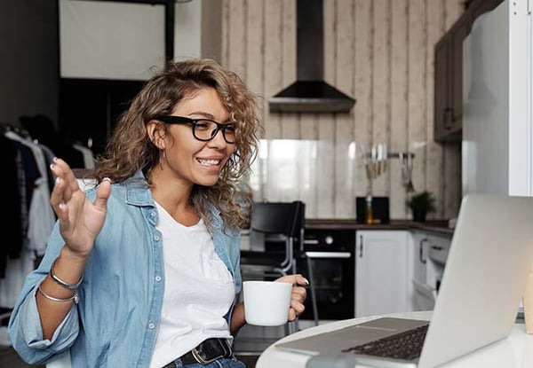 Vrouw met kop koffie achter een laptop